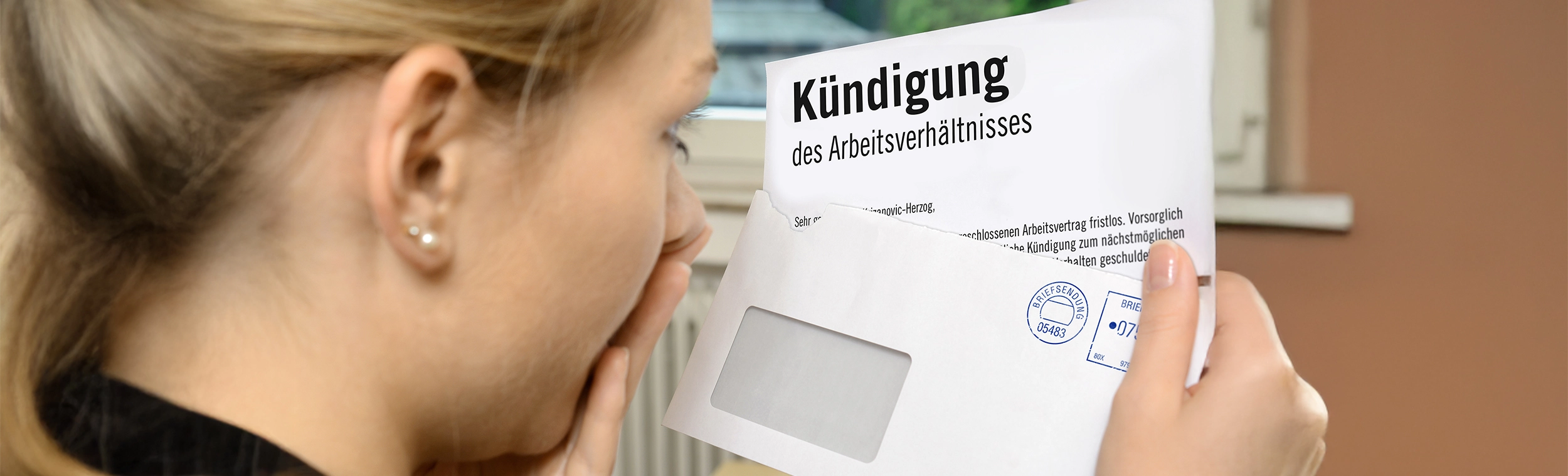 Das Bild zeigt eine Frau, die eine Kündigung in der Hand hält