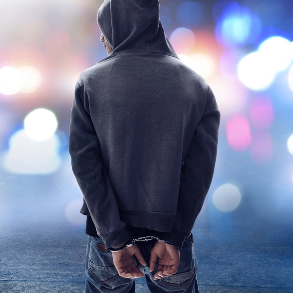 Dieses Bild zeigt einen Mann in Handschellen in einer abendlichen Stadtumgebung